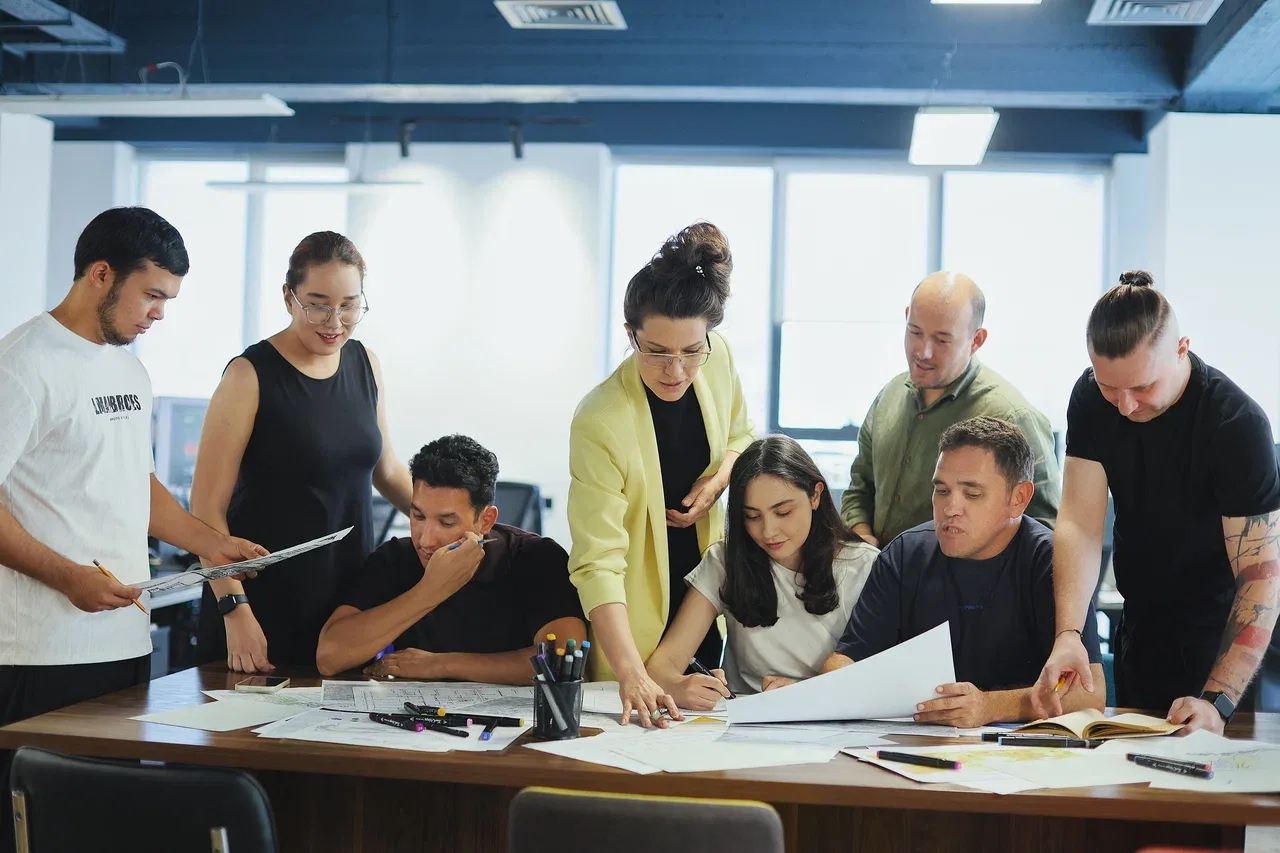 Maria Sultanova and Davron Talipov with the SAD team discussing a project over the drawings