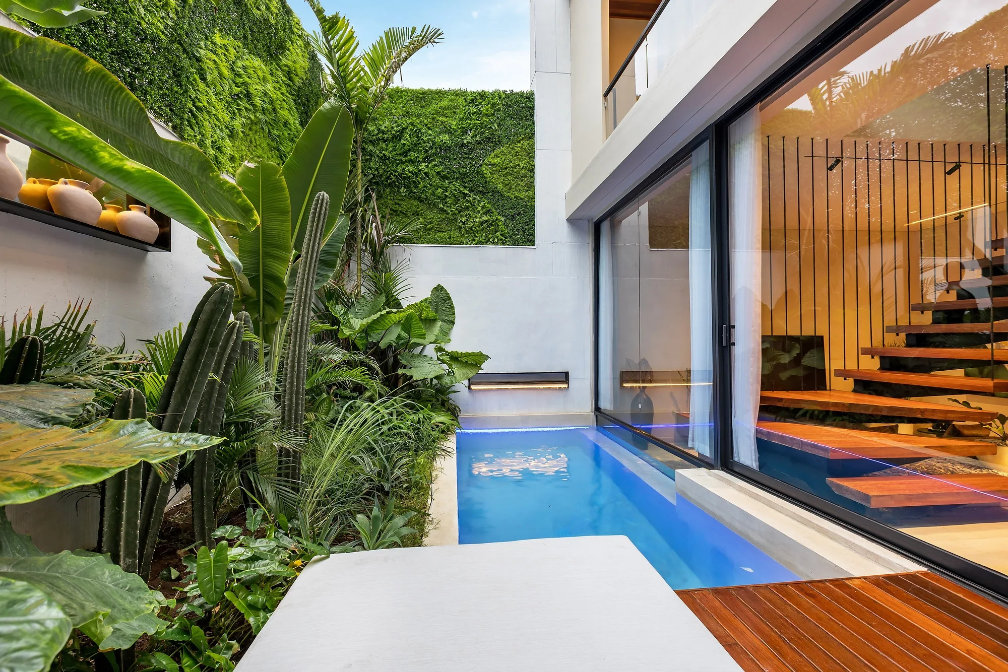The narrow villa courtyard: the pool along the glazing and a green wall