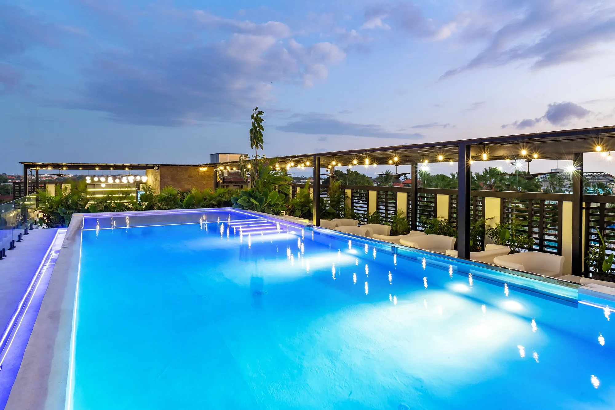 The roof at dusk: the lit pool and the view over the village