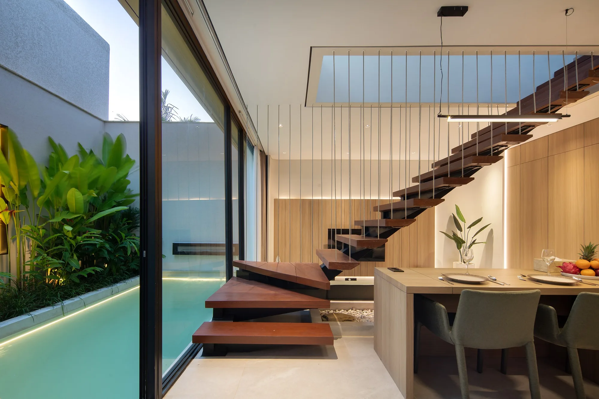 The double-height living room with an open timber stair on slender rods