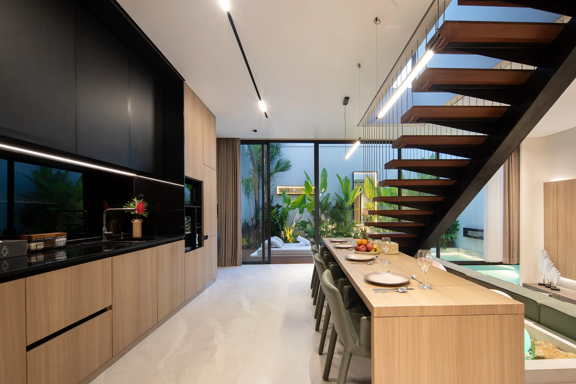 The island kitchen beneath the stair, opening to the pool courtyard