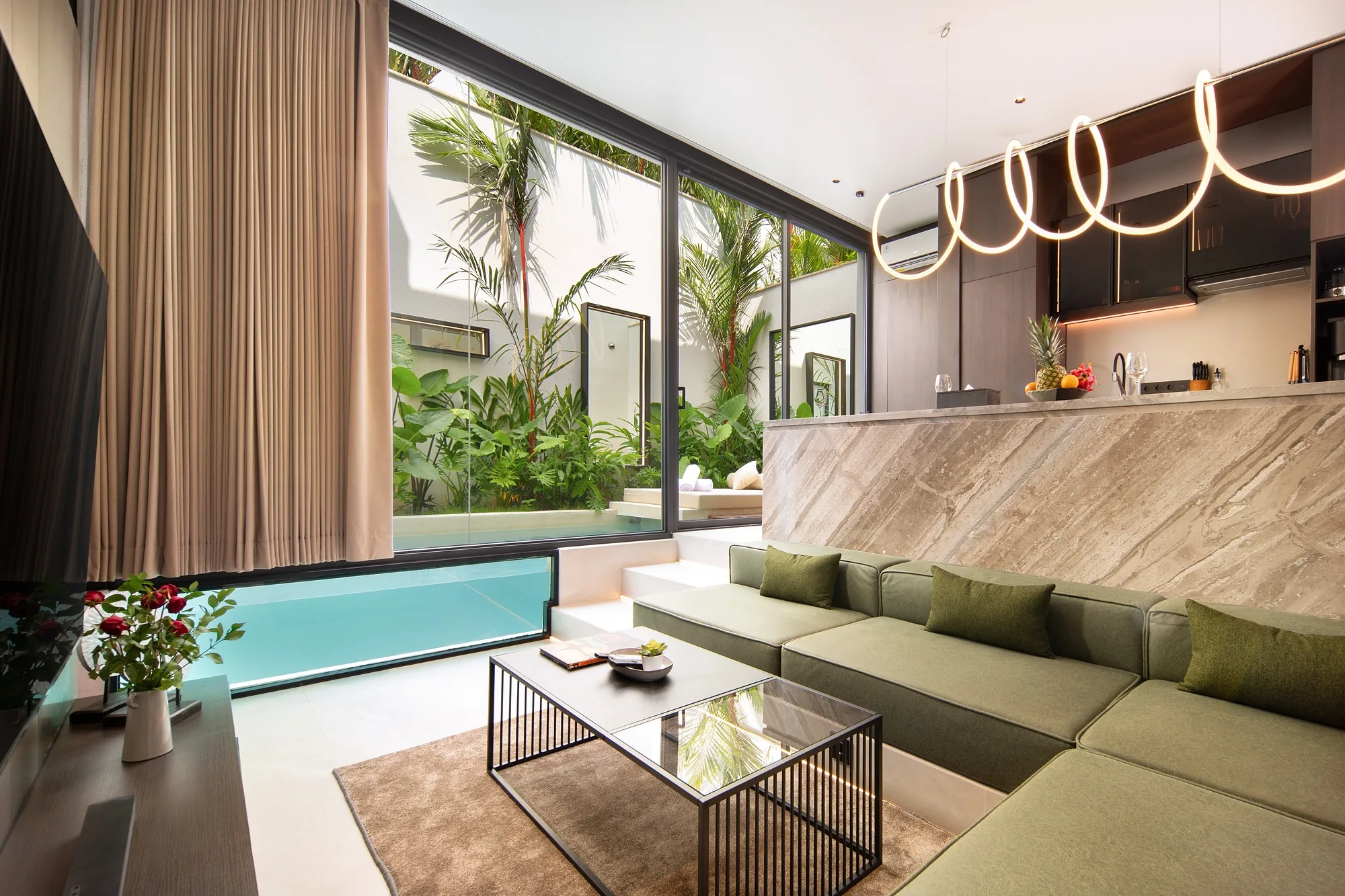 The living room opens onto the pool: full-height glazing and a green sofa by the water