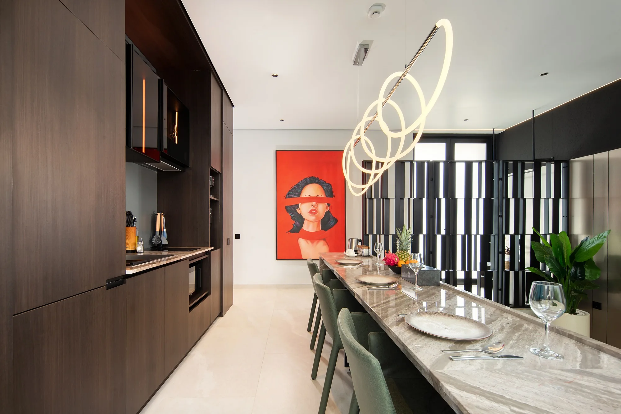 The dark kitchen reads as a separate object inside the pale volume of the villa