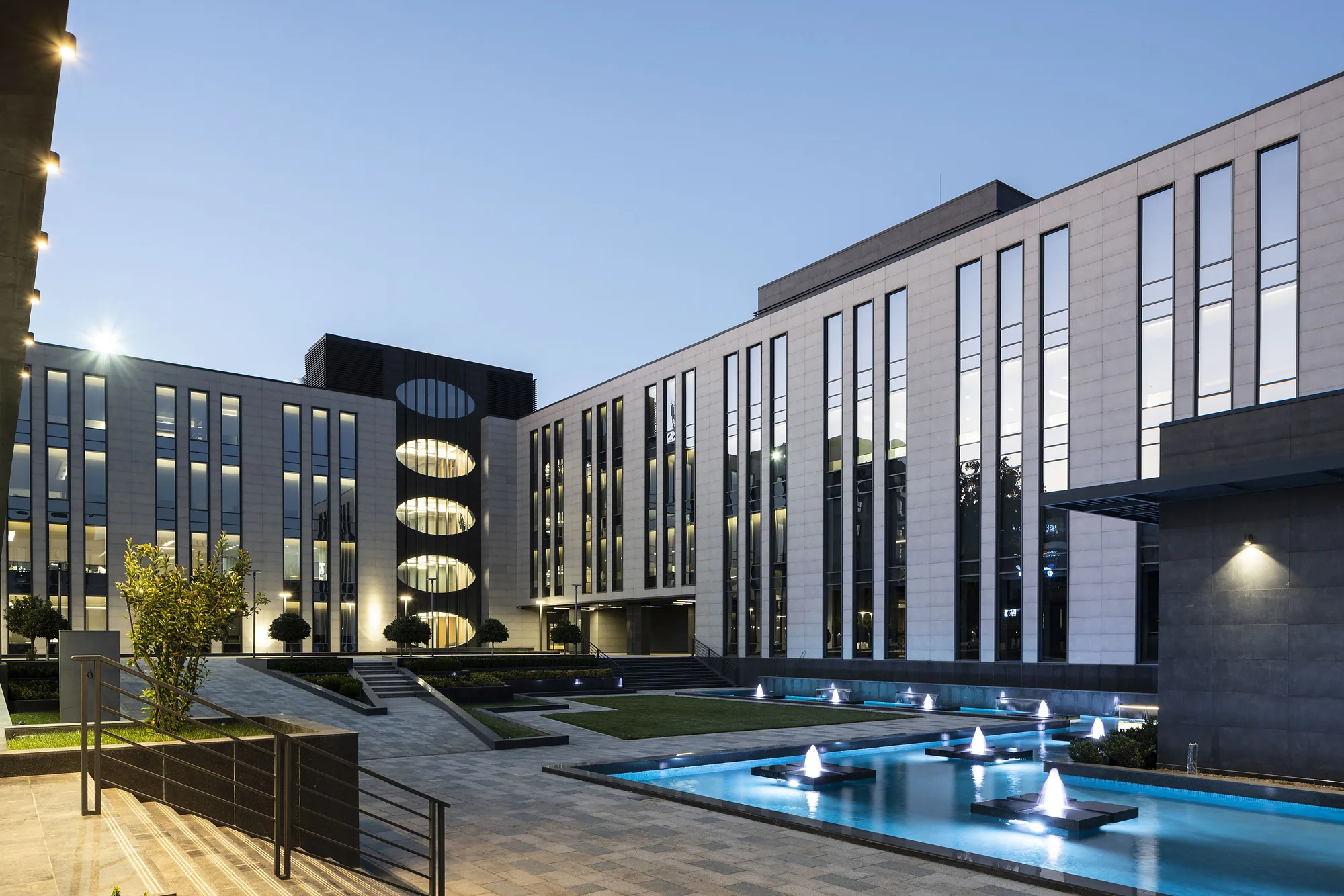 Blocks of the business centre and the fountain pool under evening lighting