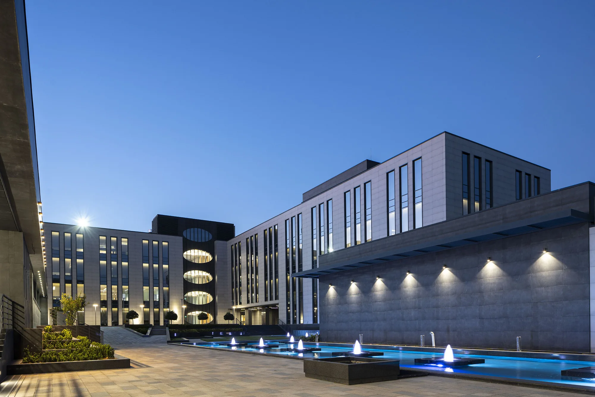 The business centre at blue hour: lit facades and fountains in the courtyard