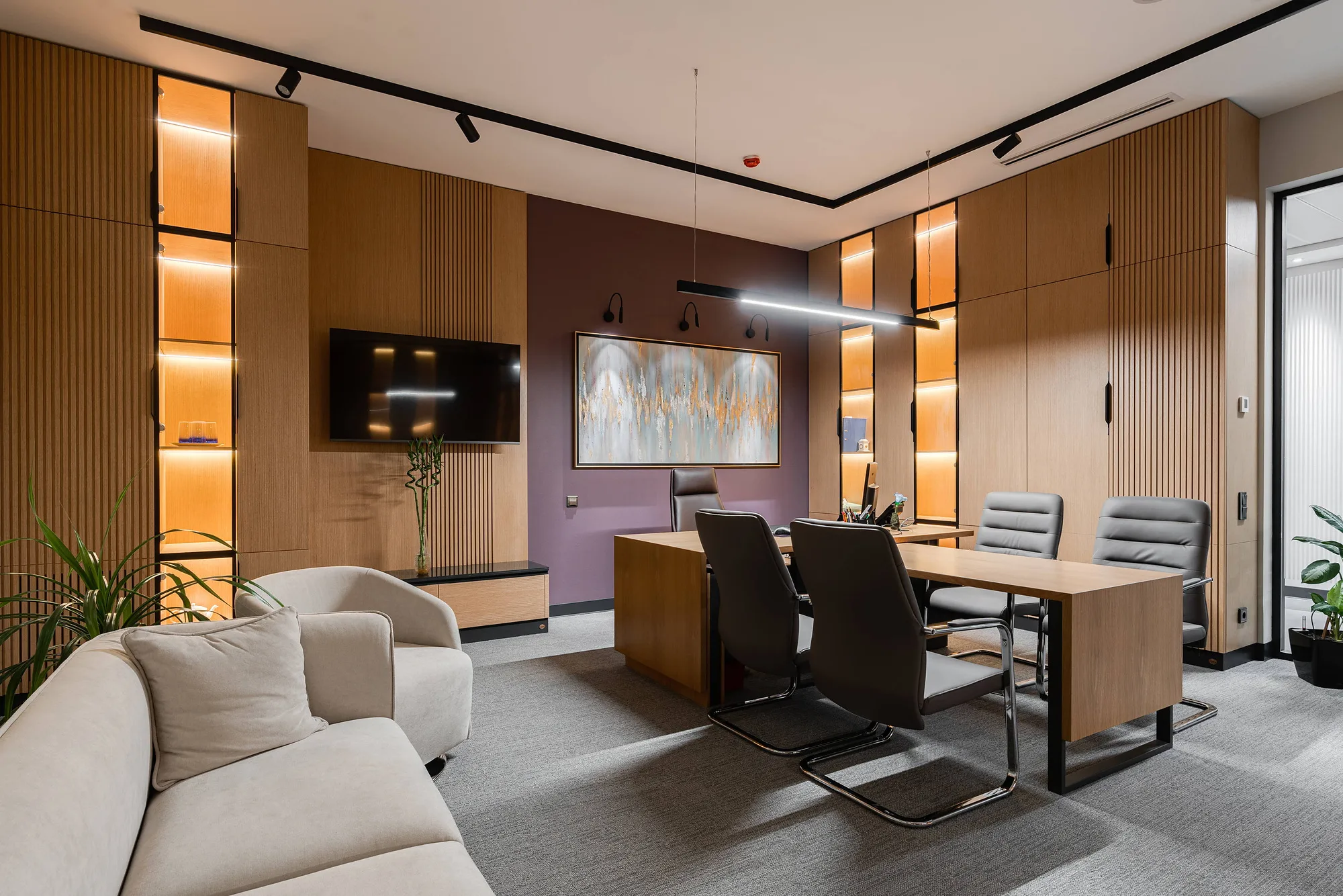 Office room with a lounge area, lit niches and a screen