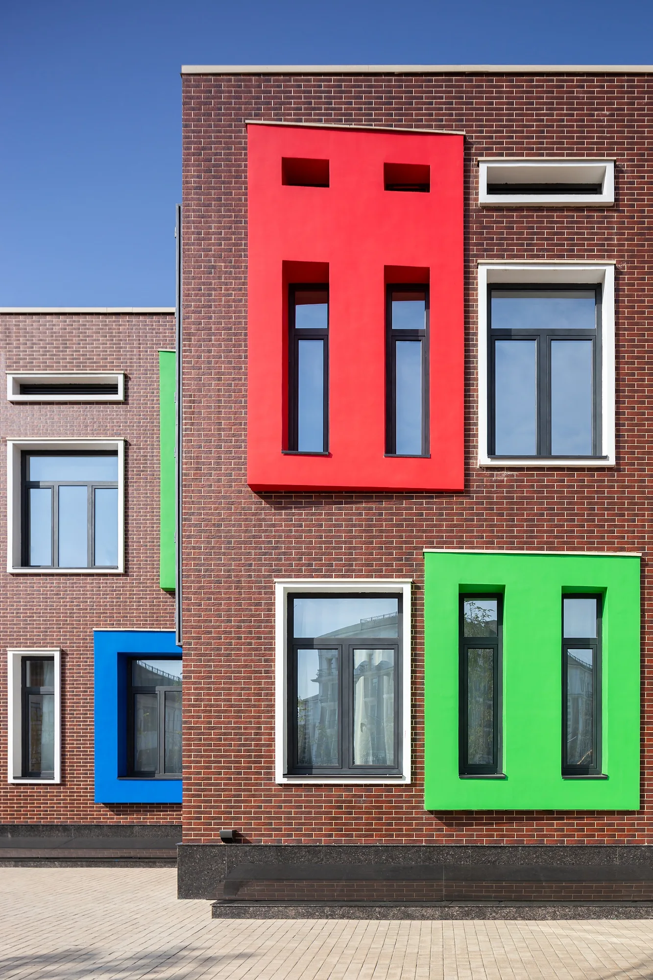 A fragment of the elevation: brick and coloured window frames