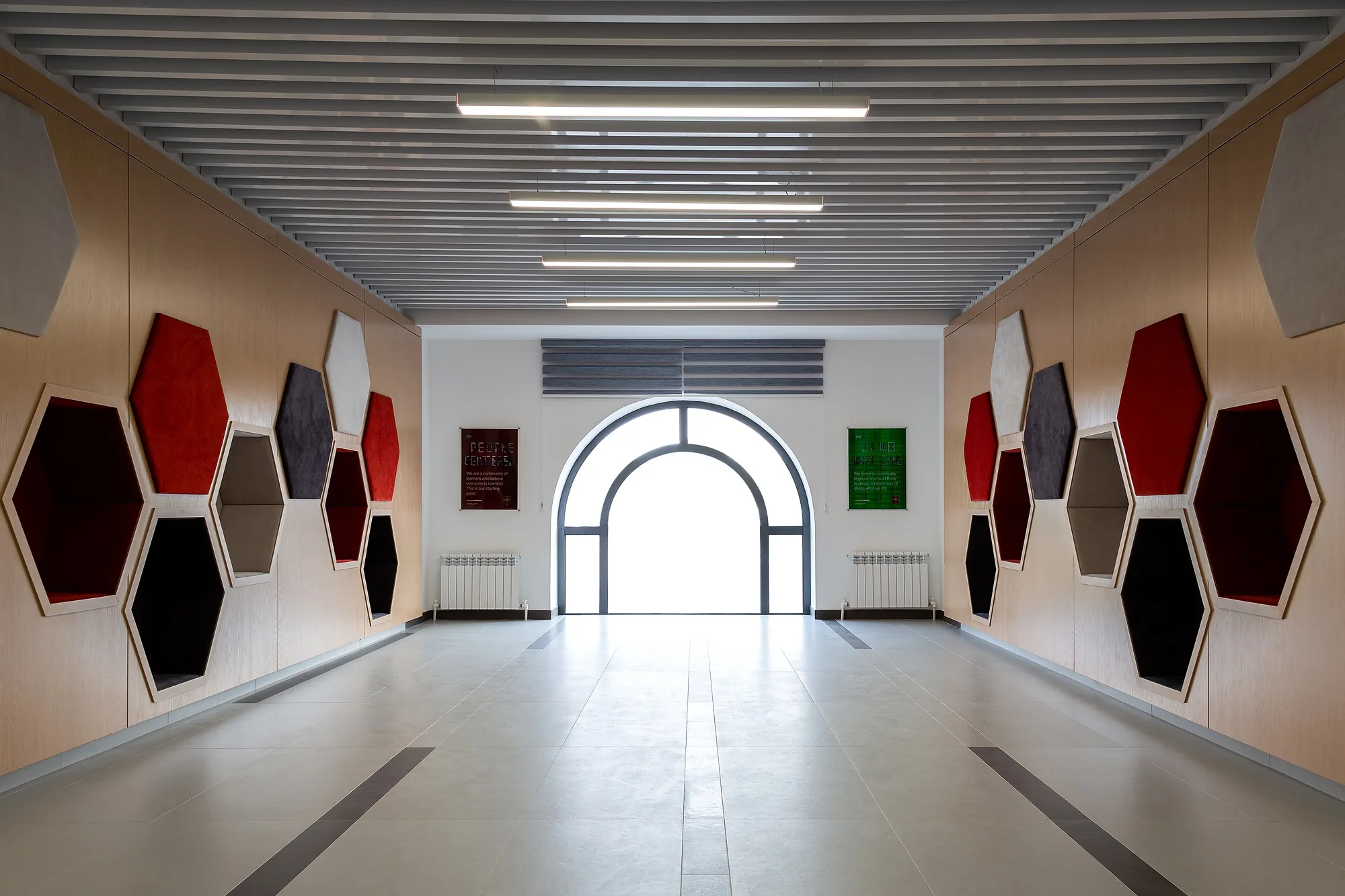 A corridor at CIS International School with hexagonal acoustic panels on both walls and an arched window at the end