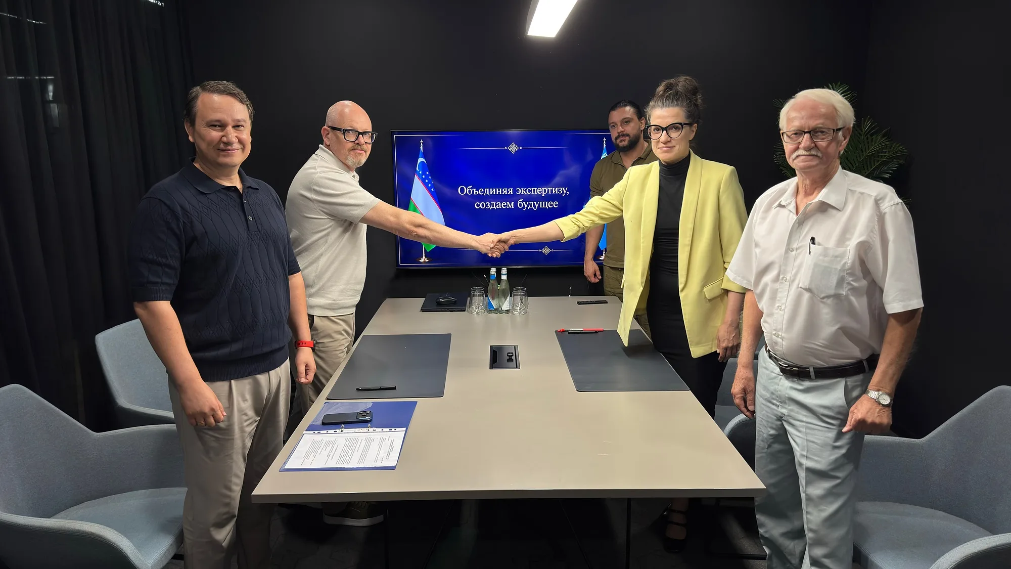 Signing a memorandum of cooperation: a handshake in front of the screen reading “Combining expertise, creating the future”