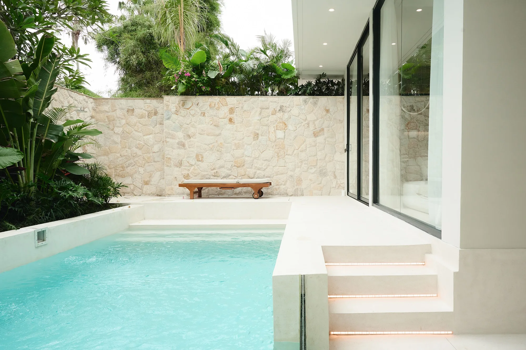 Villa courtyard: the pool with entry steps and a stone wall