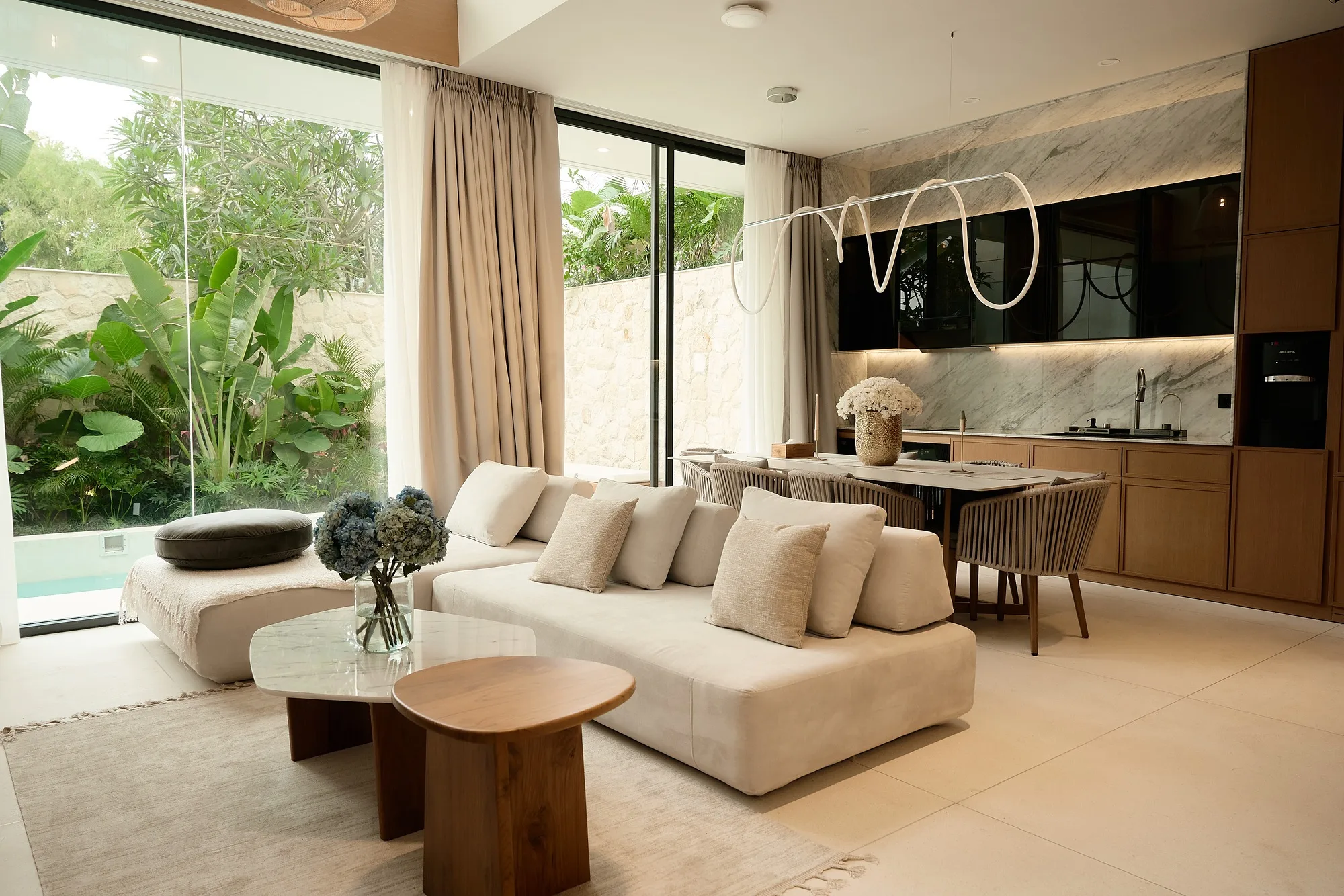 Living room of a Dream Villas house on Bali: the seating area, the kitchen-dining and the opening to the courtyard