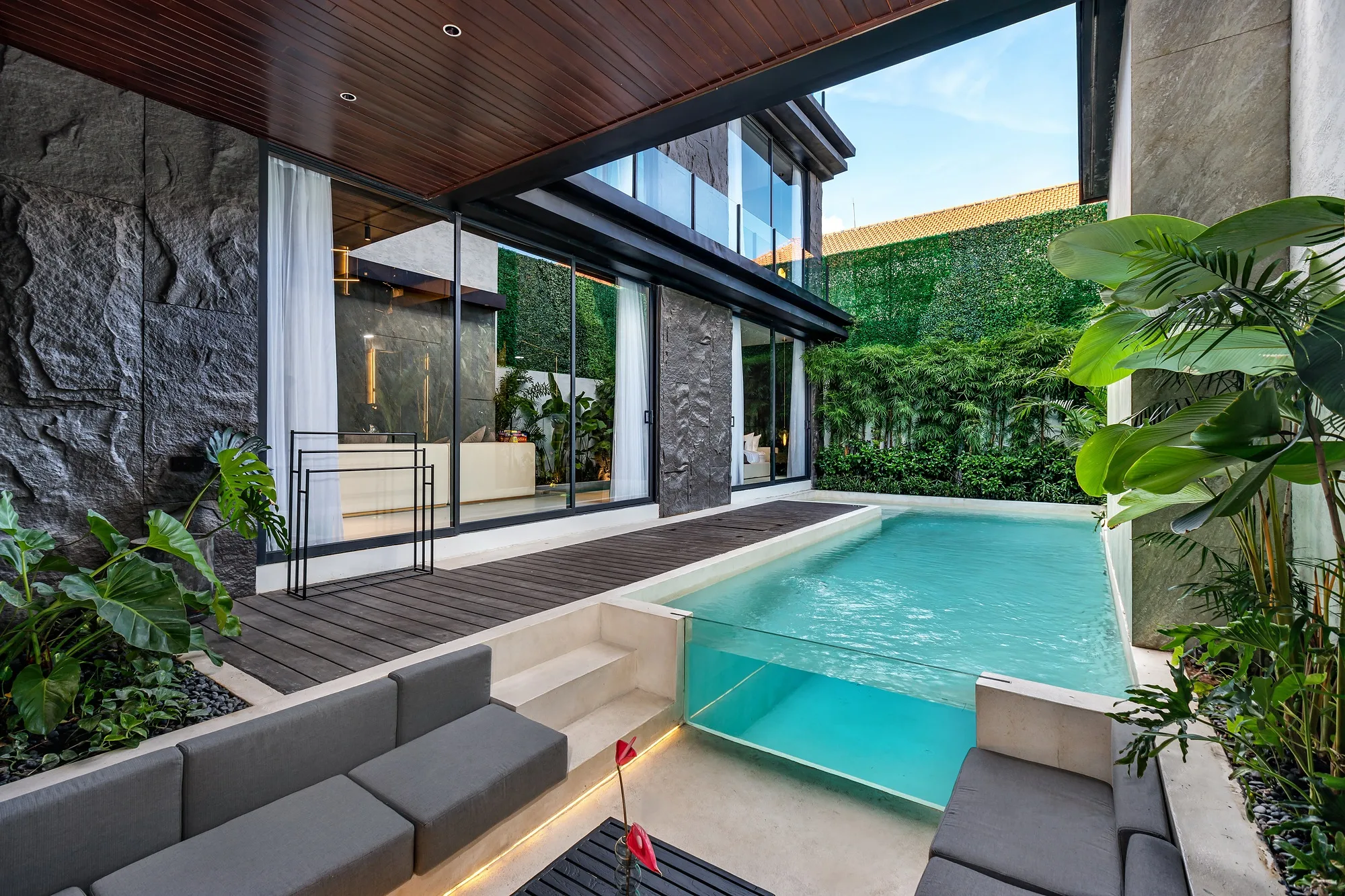 The living room opens onto the pool courtyard through sliding glazing