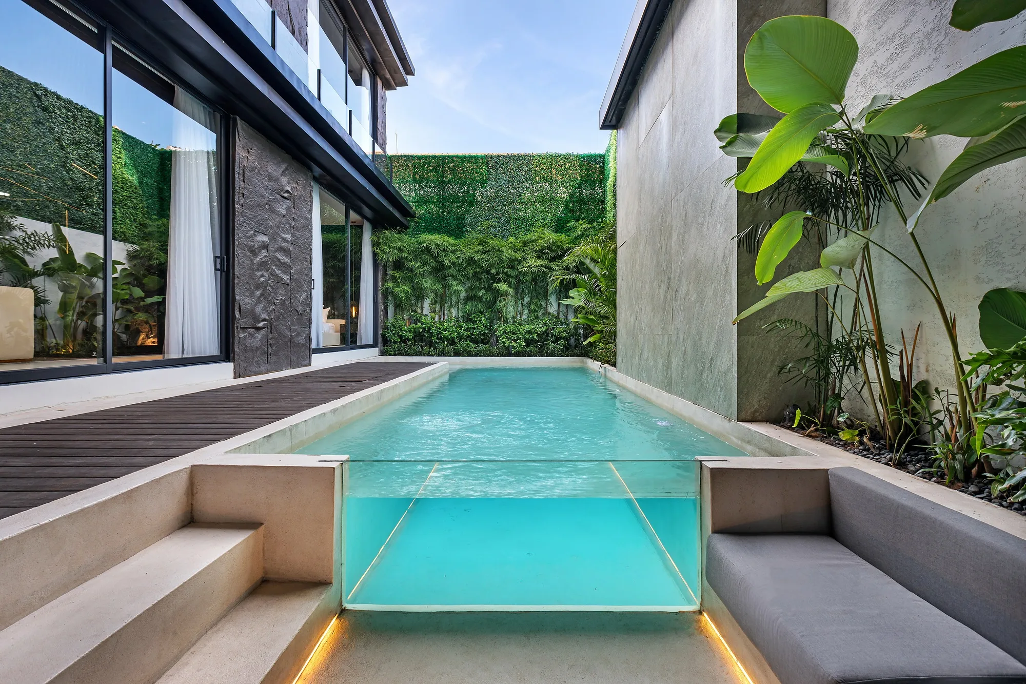 The villa courtyard: water, dark stone and a green wall screening the neighbours