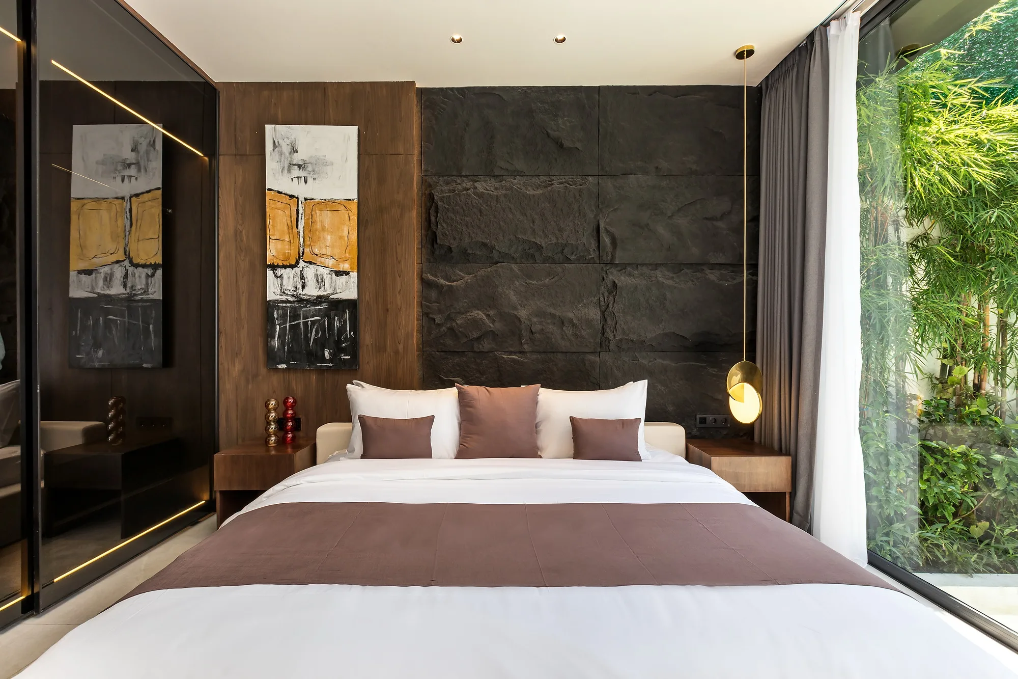 A bedroom with a stone headboard wall opening to the greenery