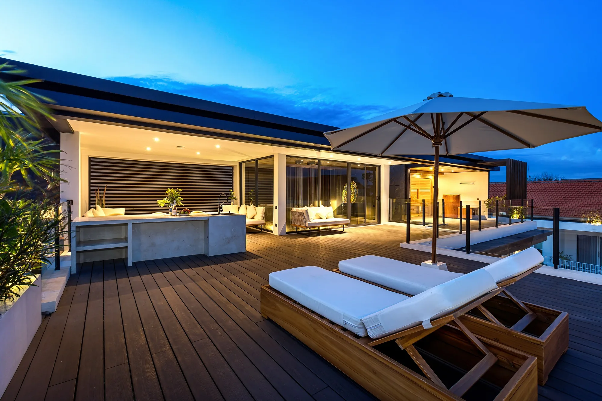 The villa roof at sunset: loungers, decking and a view over the neighbourhood roofs