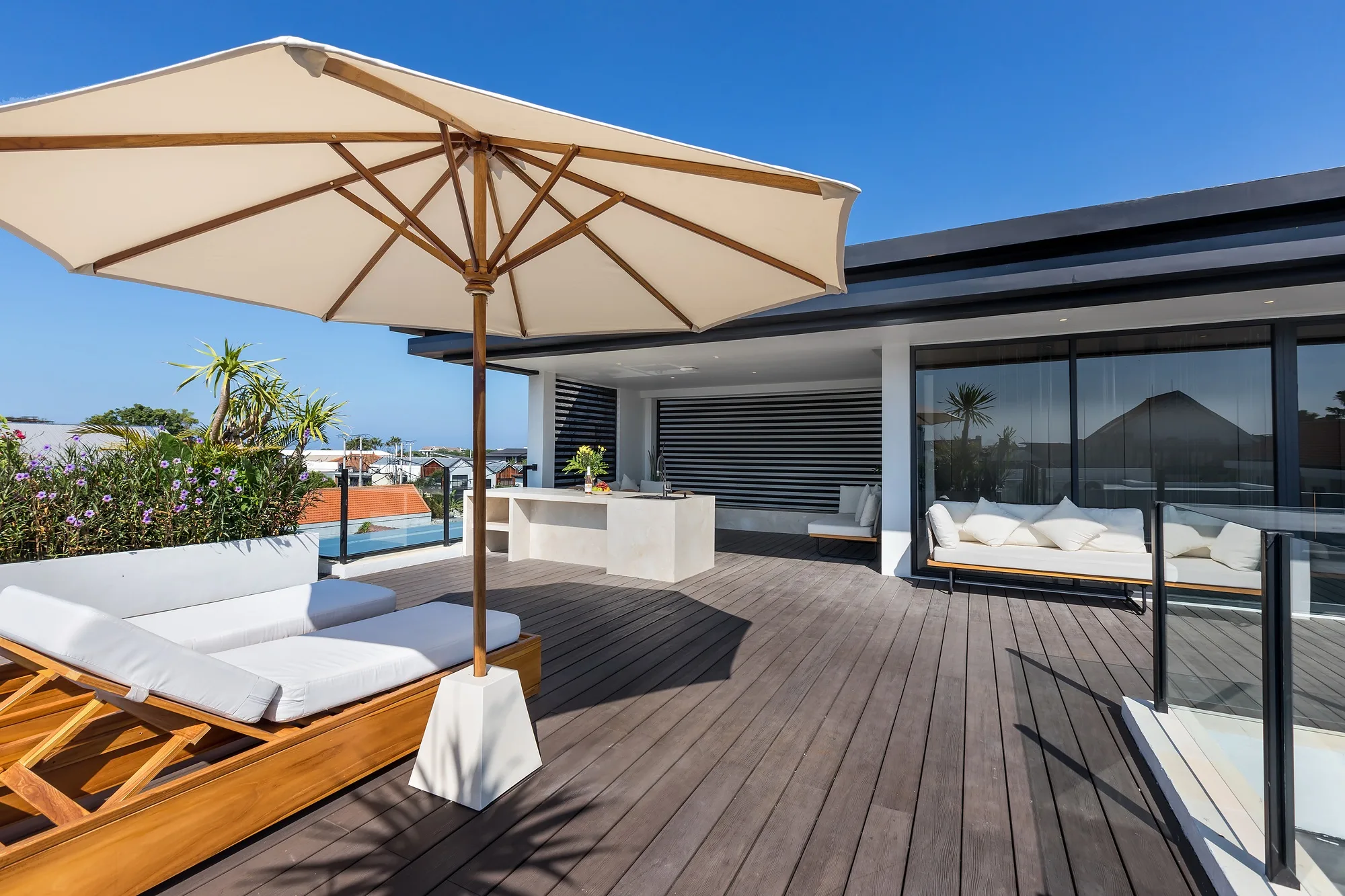 The roof in daylight: loungers under a parasol and the view over the village