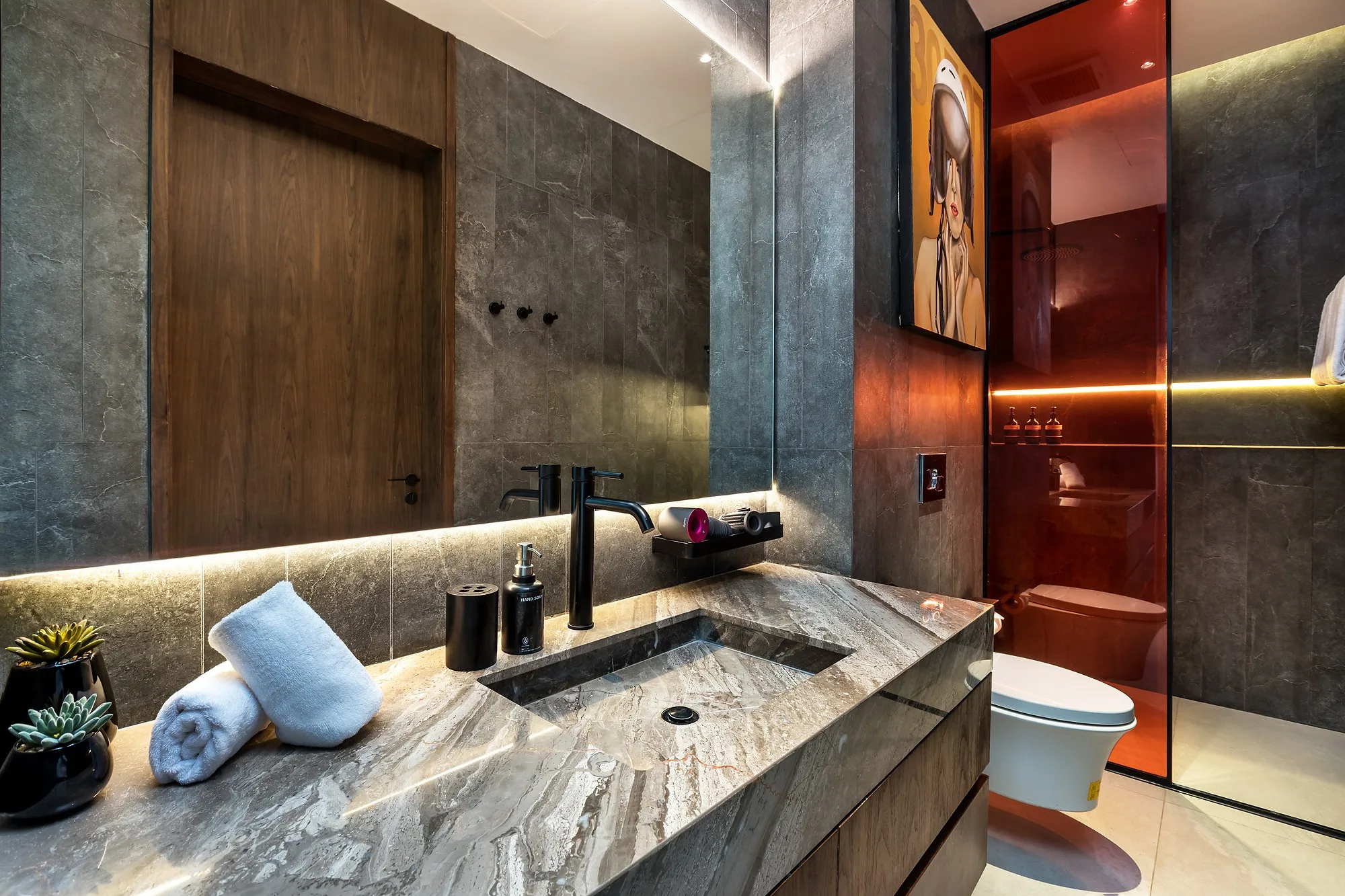 A bathroom with stone counter and lit niches