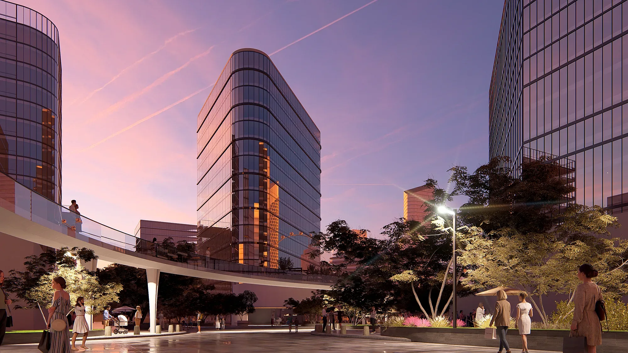 The 80-hectare district at sunset: a tower of the business core and the pedestrian bridge over the boulevard