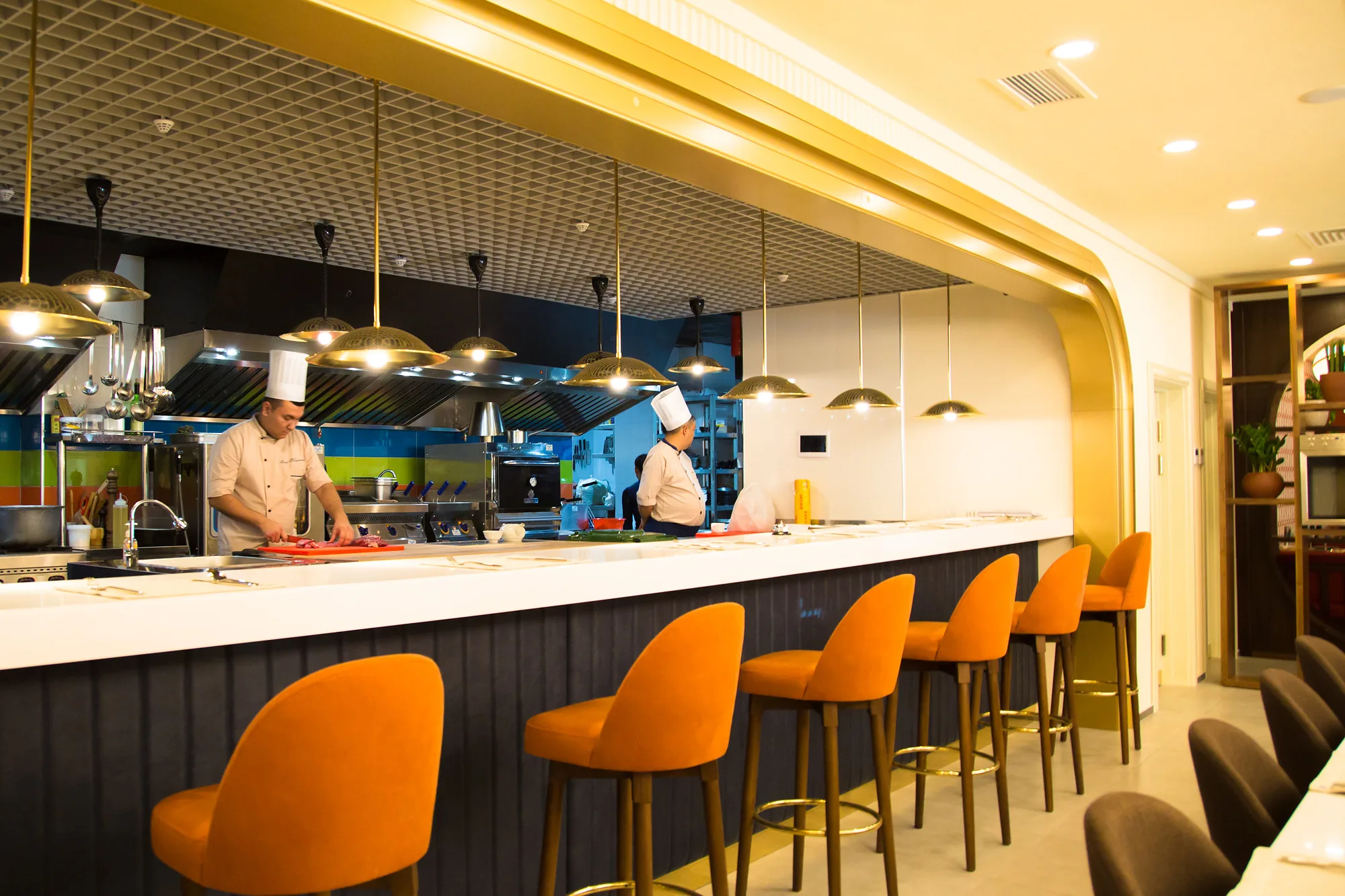 Open kitchen of Ogni Tashkenta: chefs at the pass and bar seating opposite — SAD studio