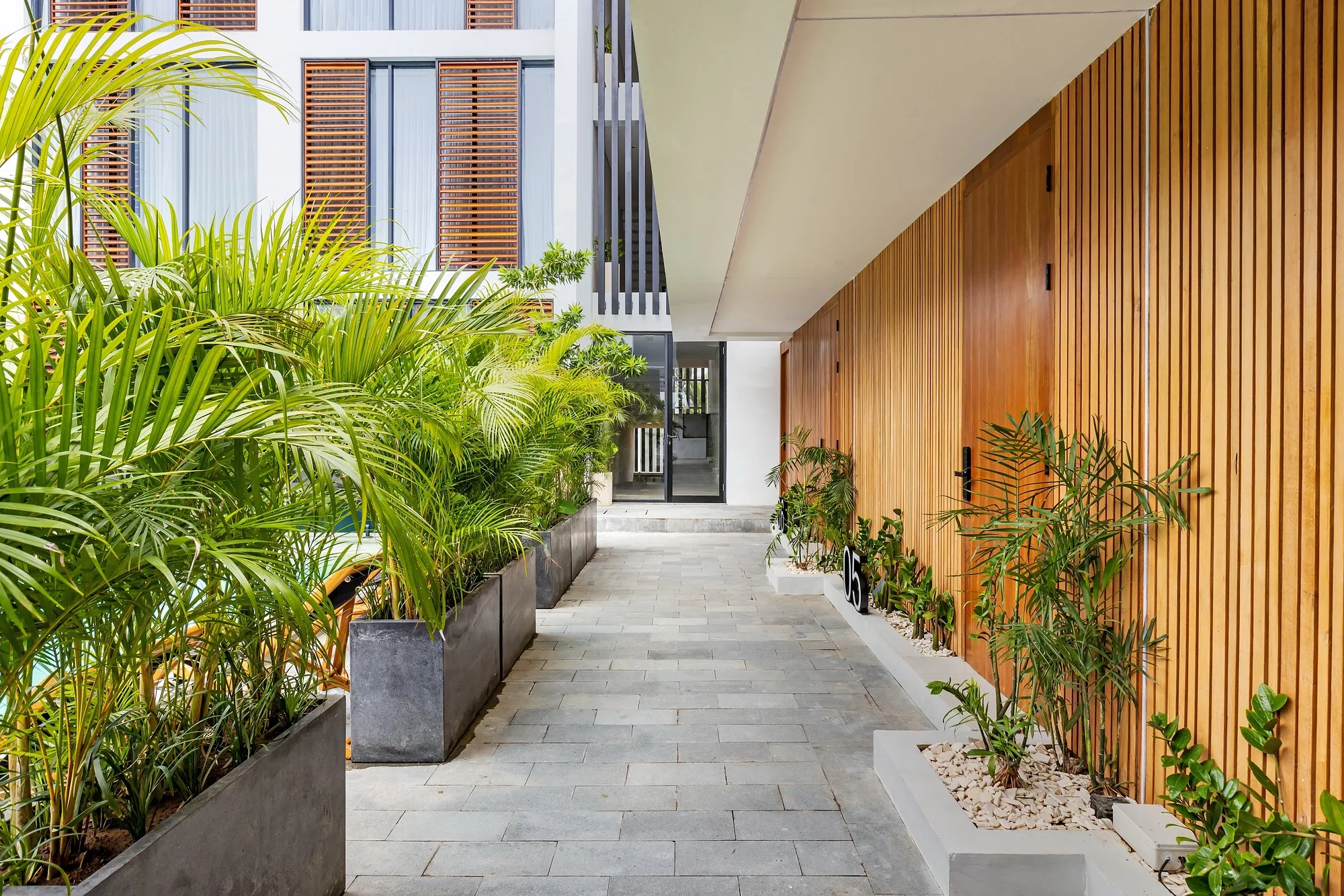 The passage along the timber facade with tropical planting