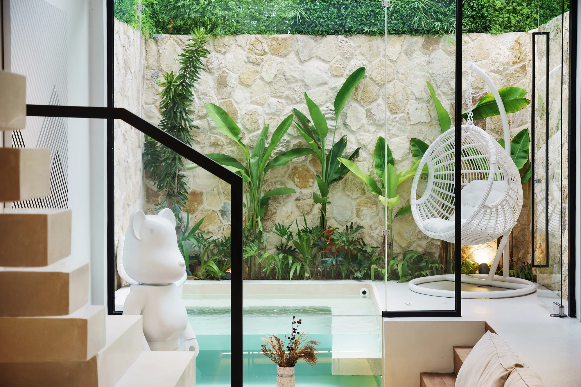 Villa courtyard: a stone wall, planting and a hanging chair