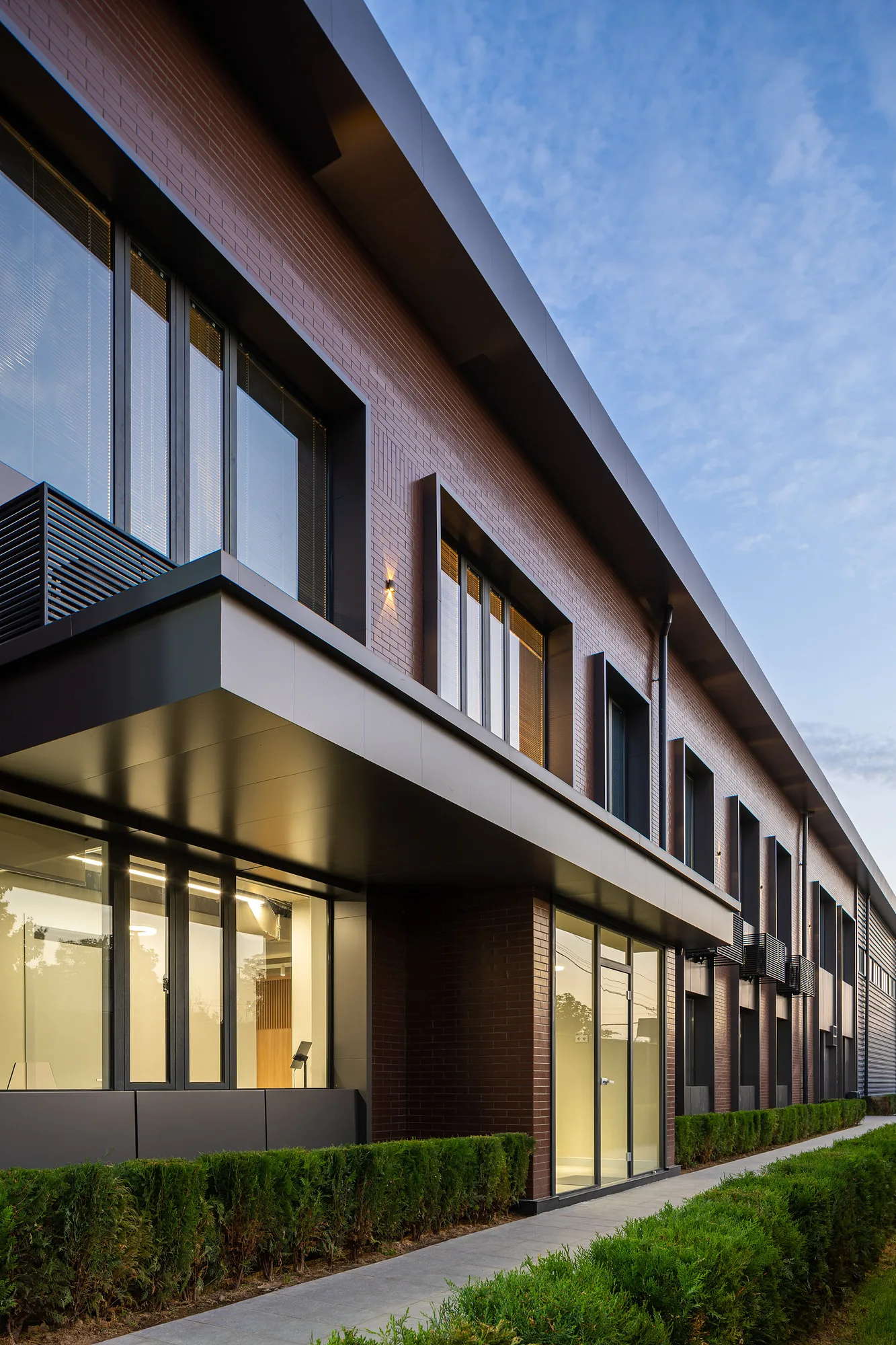The long facade of the Poytaxt Group office in Tashkent: the window band, brickwork and lit rooms — SAD studio
