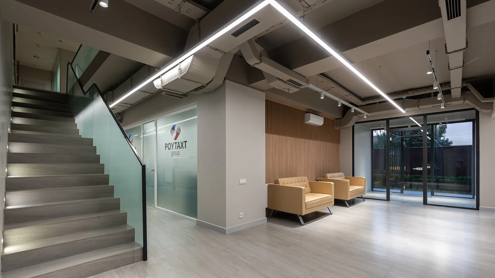 Entrance hall of the Poytaxt Group office in Tashkent: the stair with a glass balustrade and the company logo on the wall — SAD studio