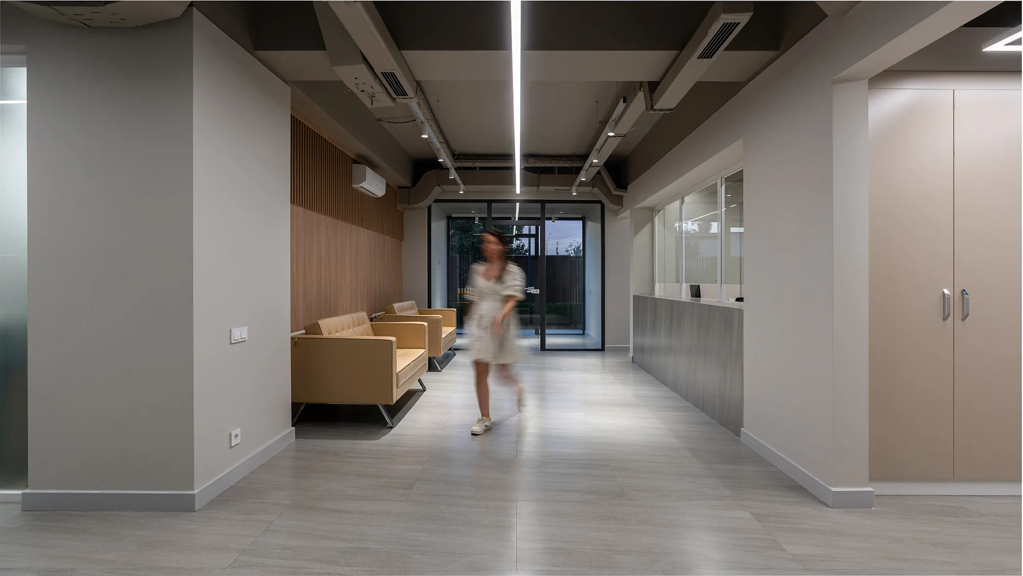 Reception of the Poytaxt Group office in Tashkent: the desk, the waiting area and linear lighting along the passage — SAD studio
