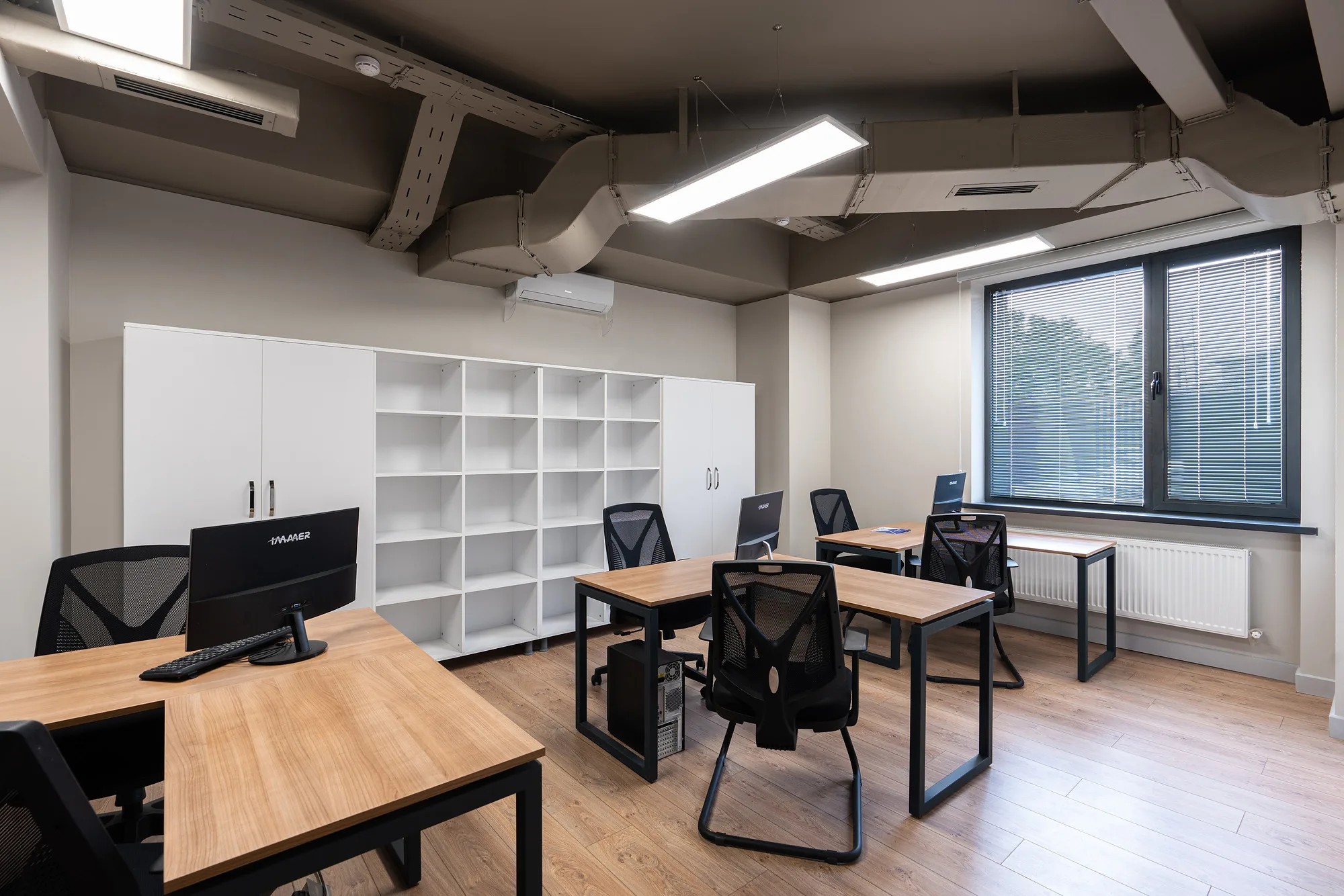 Open workspace of the Poytaxt Group office in Tashkent: desks with monitors, shelving and exposed services in the ceiling — SAD studio
