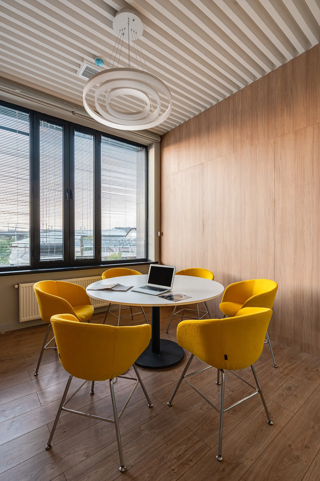 Meeting room of the Poytaxt Group office in Tashkent: a round table, yellow chairs and a ring light under the timber ceiling — SAD studio