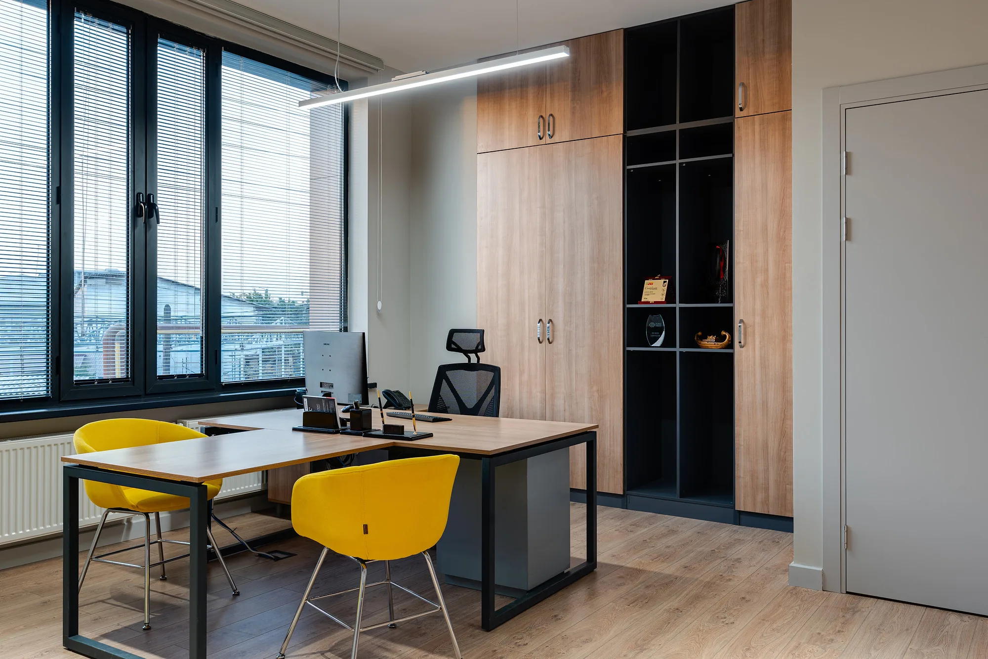 Work office at Poytaxt Group in Tashkent: a desk by the blinded window and a timber-and-metal shelving unit — SAD studio