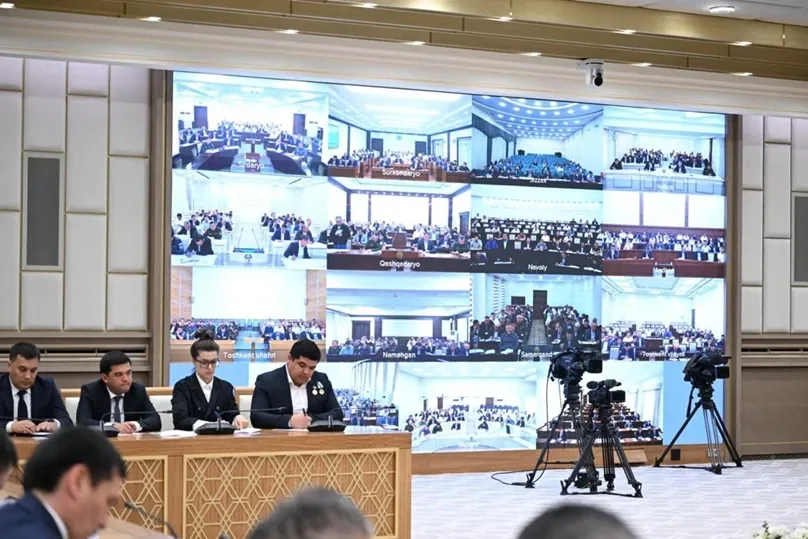 A videoconference meeting on the construction industry chaired by the President of Uzbekistan: participants at the table and regional feeds on the screen