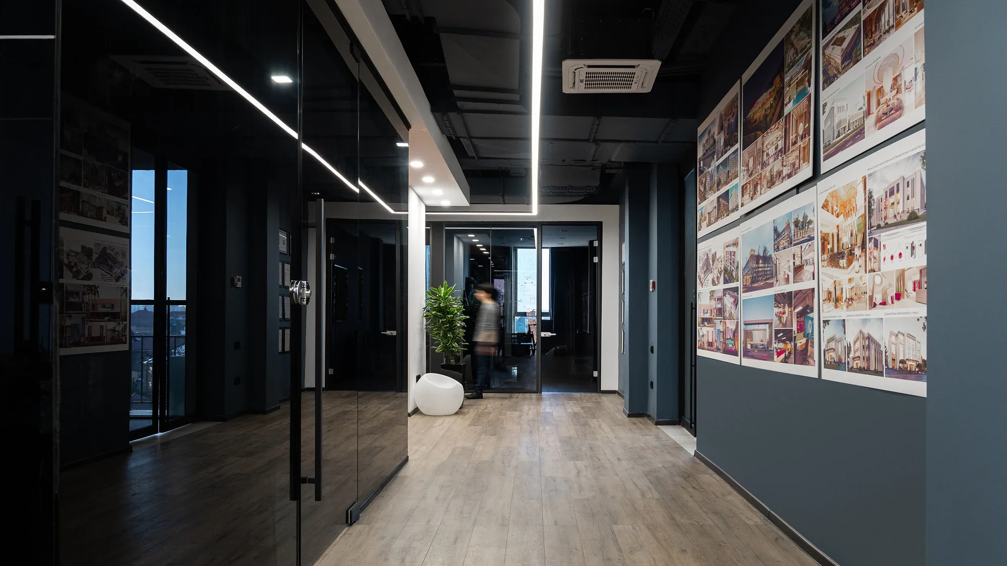 Corridor of the SAD studio office: project boards along the wall and linear light in the dark ceiling — SAD studio