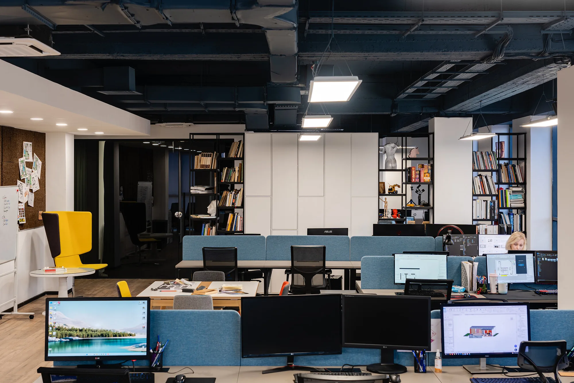 Working core of SAD studio: monitors with projects, acoustic screens and a yellow chair in the aisle — SAD studio