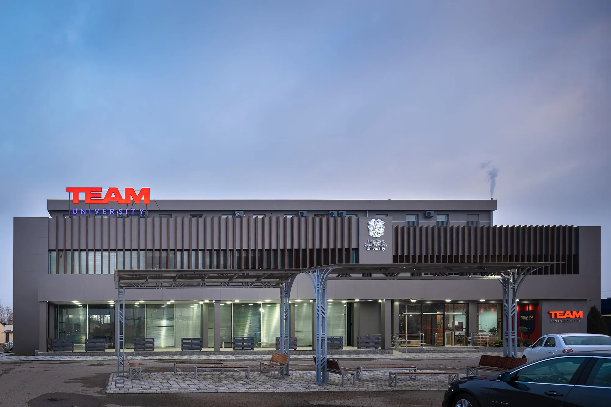 TEAM University in Tashkent as built: the main facade with timber fins, the glazed ground floor and the entrance canopy — SAD studio