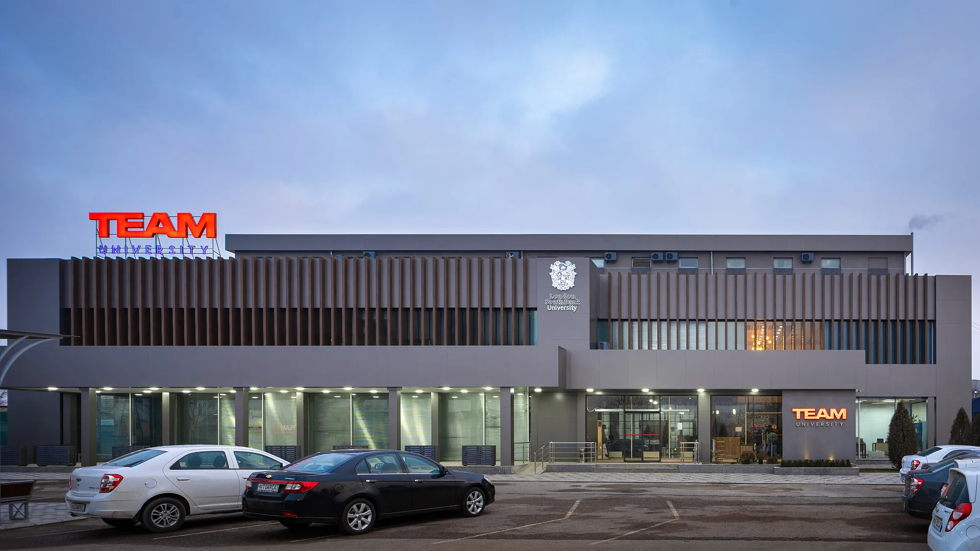 The full main facade of TEAM University in Tashkent: two levels of fins above the ground-floor glazing — SAD studio