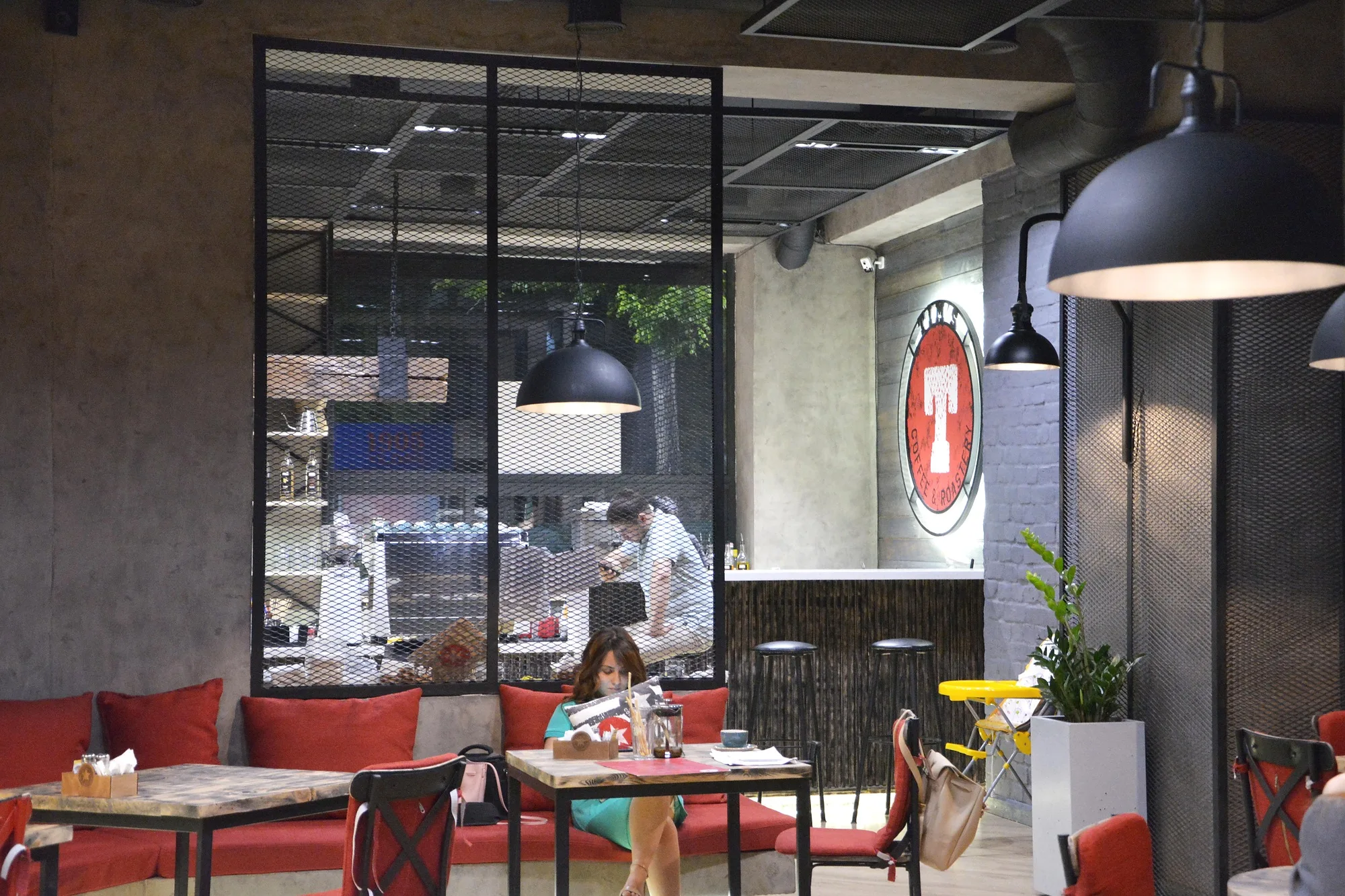 TIM'S Coffee & Roastery in Tashkent: banquettes by the glazed partition and the logo — SAD studio
